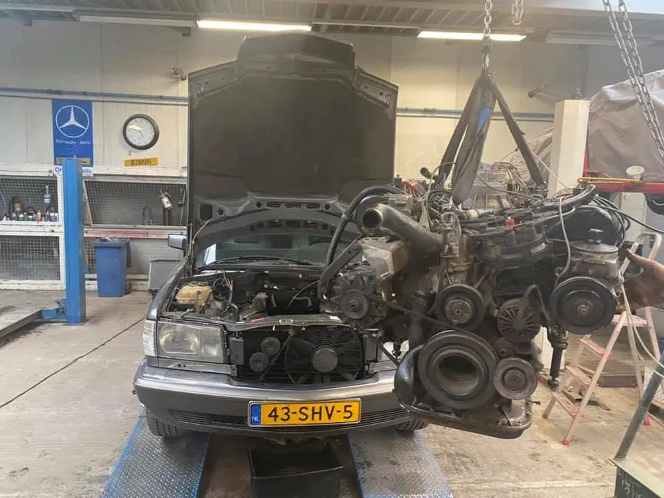 W124 met open motorruimte terwijl de motor eruit wordt getakeld